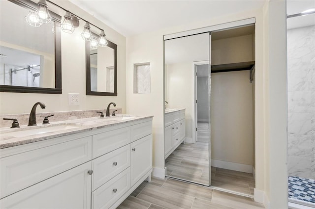 full bathroom with double vanity, wood finish floors, walk in shower, and a sink