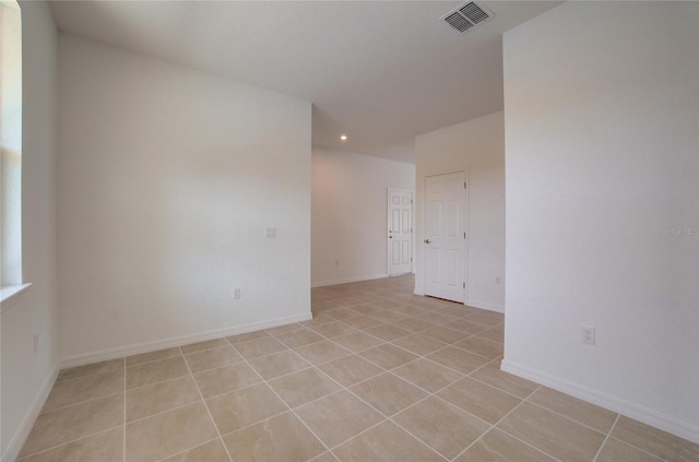 empty room with light tile patterned flooring, visible vents, and baseboards