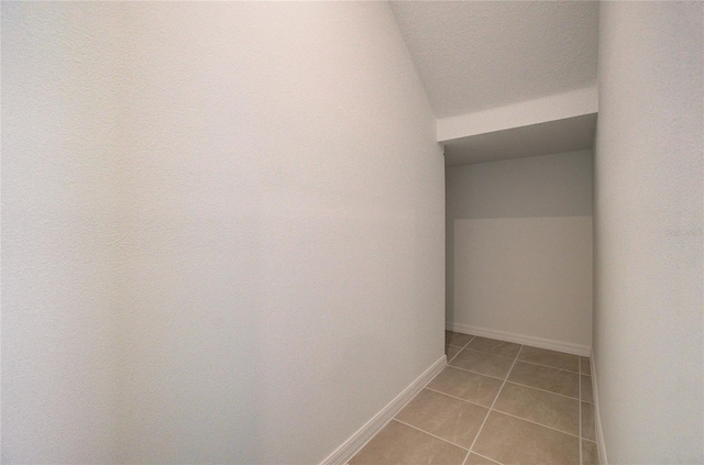 corridor with light tile patterned floors and baseboards