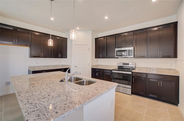 kitchen with dark brown cabinets, appliances with stainless steel finishes, light stone countertops, and a sink