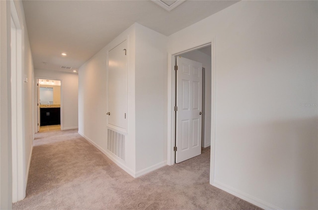 hallway with visible vents, recessed lighting, light colored carpet, and baseboards