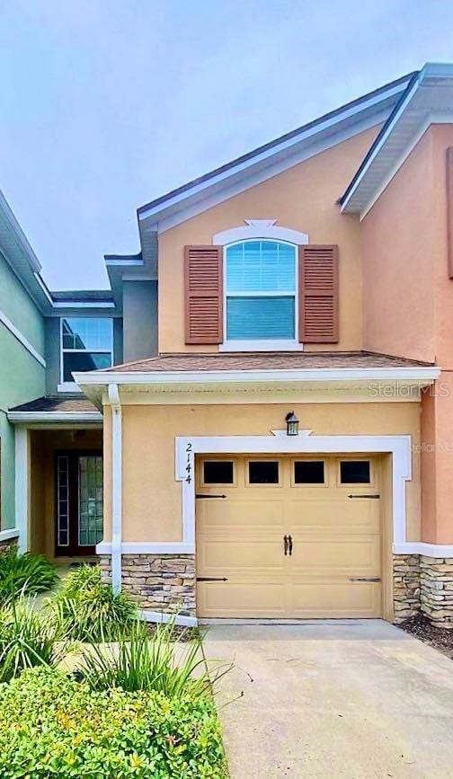 view of front of house with stone siding, stucco siding, driveway, and a garage