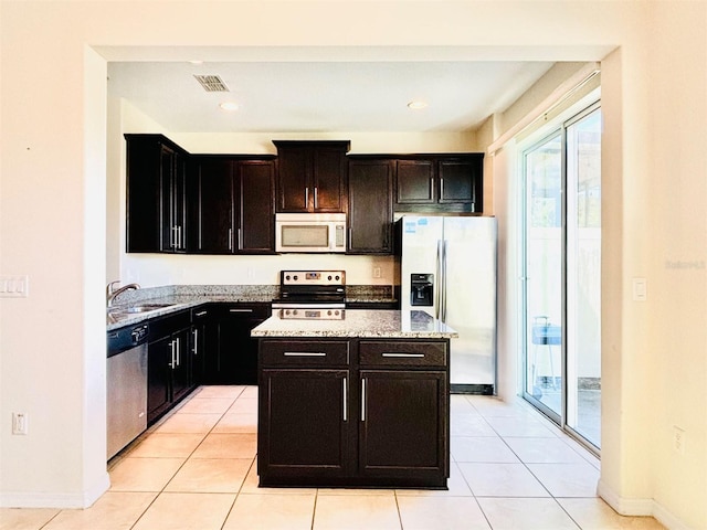 kitchen with visible vents, a sink, appliances with stainless steel finishes, light tile patterned floors, and light stone countertops