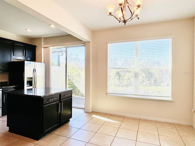 kitchen featuring light tile patterned floors, baseboards, refrigerator with ice dispenser, and dark cabinets