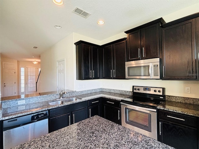 kitchen featuring visible vents, recessed lighting, dark stone countertops, stainless steel appliances, and a sink