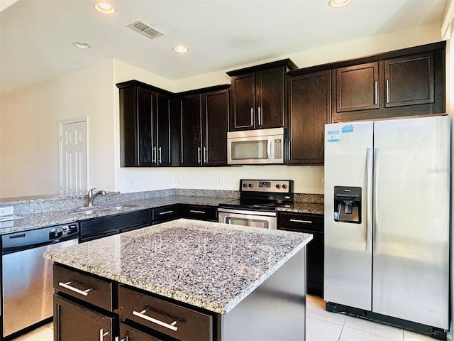 kitchen with visible vents, a sink, appliances with stainless steel finishes, light tile patterned flooring, and light stone countertops