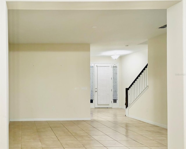 unfurnished room with baseboards, light tile patterned flooring, and stairs