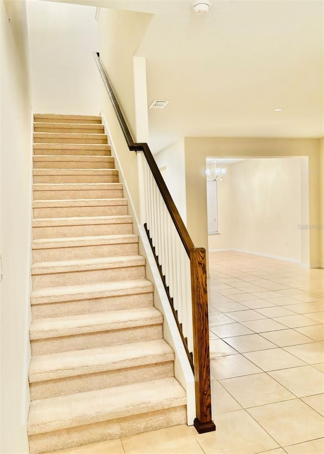 stairs with tile patterned floors, visible vents, and an inviting chandelier