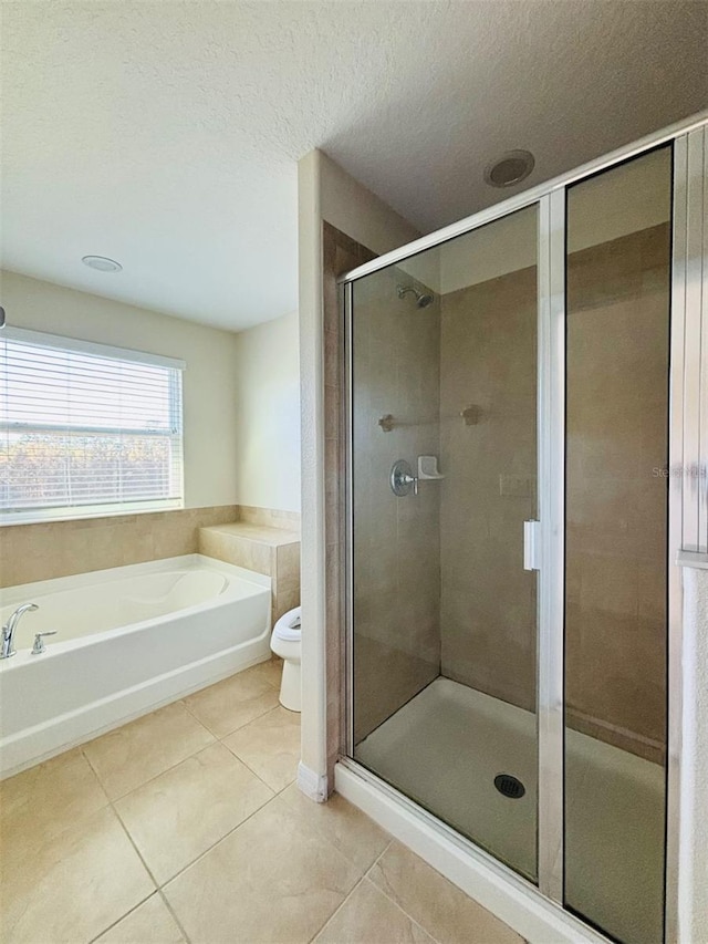 full bath featuring a bath, a stall shower, a textured ceiling, tile patterned floors, and toilet