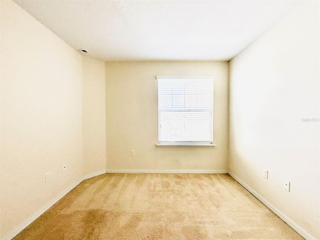 spare room featuring baseboards and light carpet