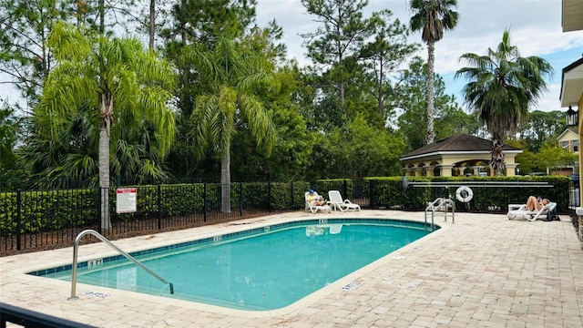 community pool with a patio area and fence