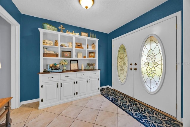 foyer featuring light tile patterned floors, french doors, baseboards, and a textured ceiling