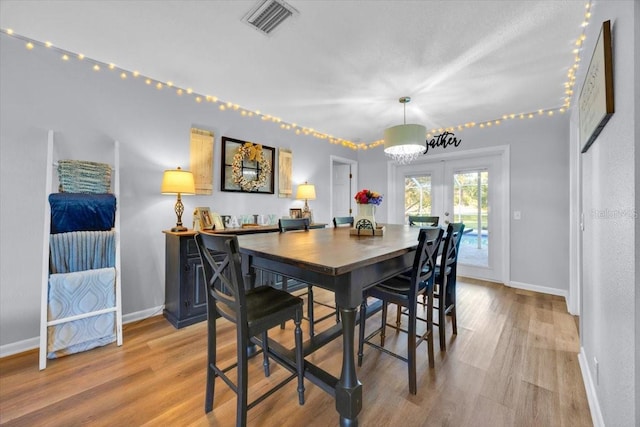 dining room with visible vents, french doors, light wood-type flooring, and baseboards