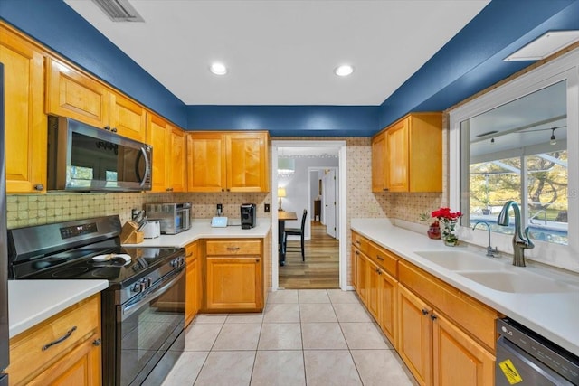 kitchen with stainless steel microwave, visible vents, dishwashing machine, black electric range oven, and a sink