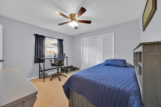 bedroom with baseboards, ceiling fan, a closet, a textured ceiling, and light carpet