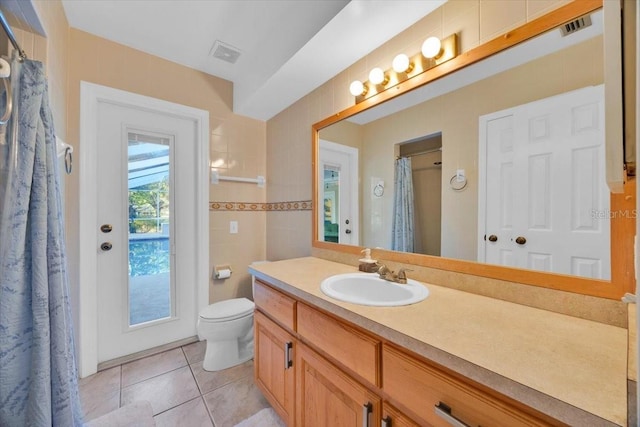 bathroom featuring tile patterned floors, visible vents, toilet, and tile walls