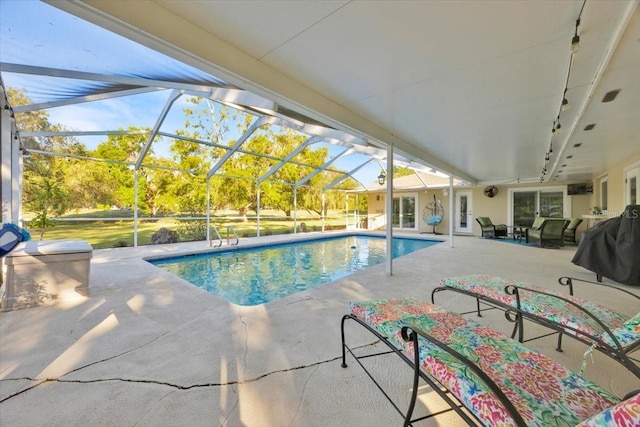 outdoor pool featuring glass enclosure and a patio