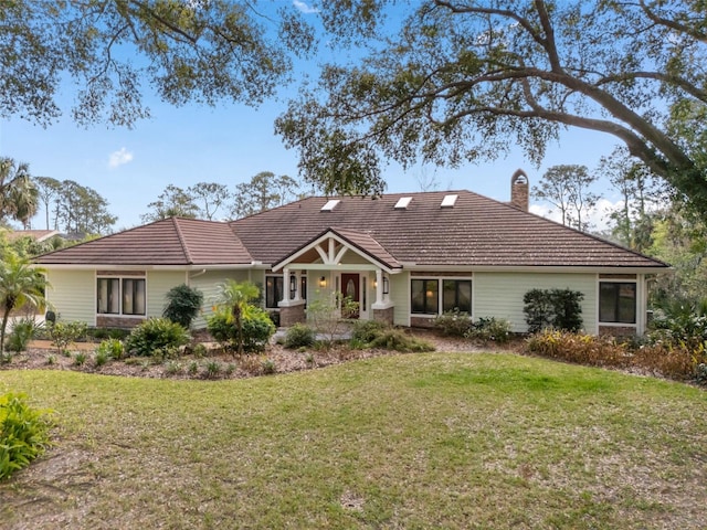 view of front of home with a chimney, a front yard, and a tile roof