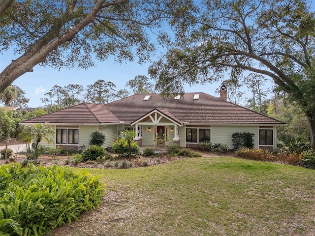 view of front of house featuring a tiled roof, a chimney, and a front lawn