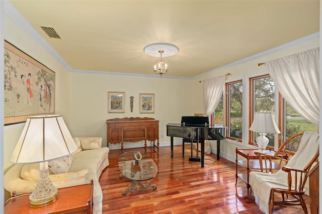 living area with wood finished floors, baseboards, visible vents, an inviting chandelier, and ornamental molding