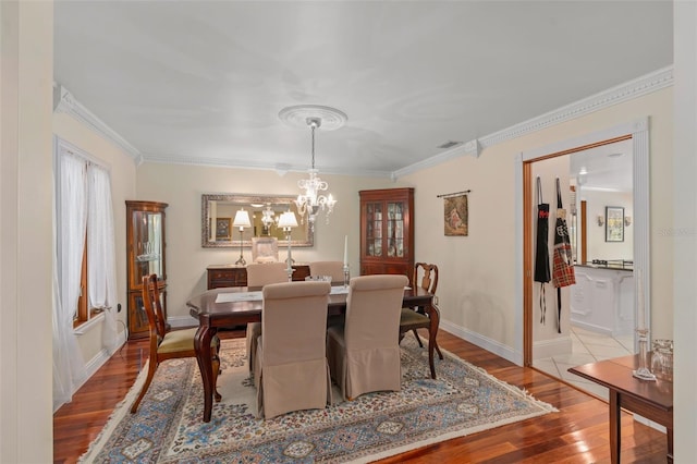 dining space with visible vents, wood finished floors, baseboards, and ornamental molding