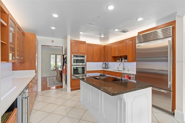 kitchen featuring light tile patterned floors, brown cabinetry, visible vents, a sink, and stainless steel appliances