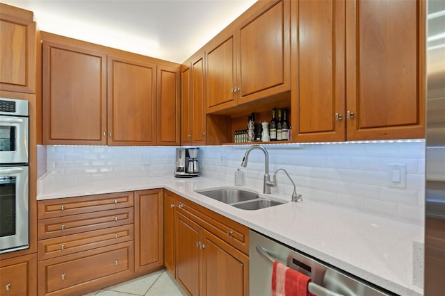 kitchen with brown cabinetry, stainless steel appliances, tasteful backsplash, and a sink