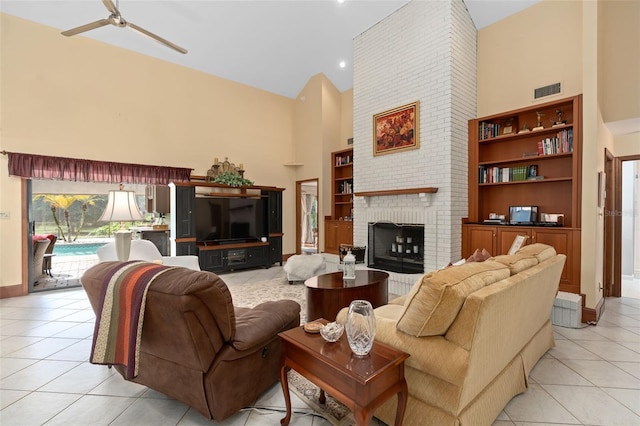 living room featuring a high ceiling, light tile patterned floors, a fireplace, and visible vents