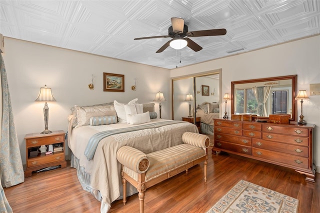 bedroom featuring a closet, an ornate ceiling, ceiling fan, and wood finished floors