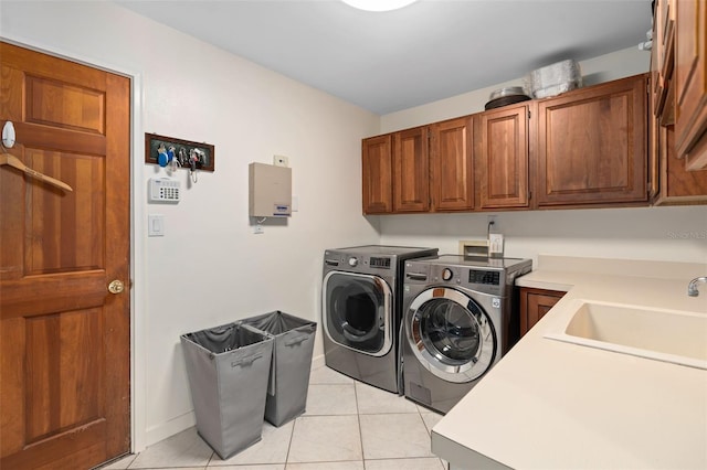 clothes washing area featuring baseboards, light tile patterned flooring, cabinet space, a sink, and independent washer and dryer