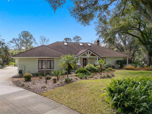 single story home with a chimney, a tile roof, concrete driveway, and a front yard