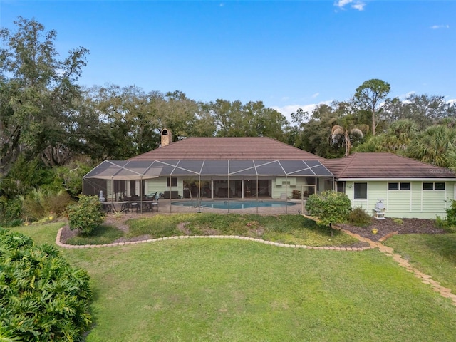 rear view of house with an outdoor pool, glass enclosure, a yard, and a chimney