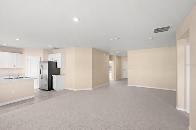 unfurnished living room with recessed lighting, light colored carpet, visible vents, and a sink