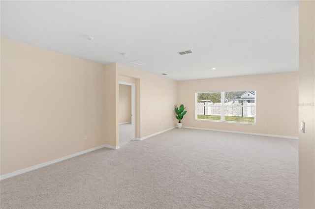 unfurnished room with visible vents, light colored carpet, and baseboards