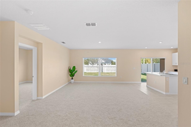 spare room with visible vents, light carpet, a sink, recessed lighting, and baseboards