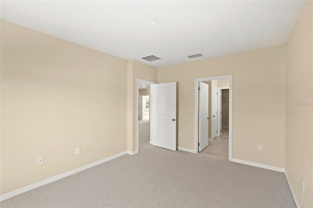 unfurnished bedroom with visible vents, light colored carpet, and baseboards