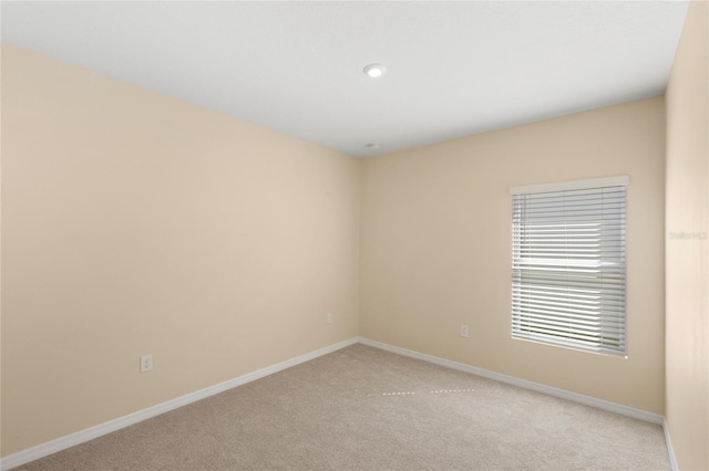 unfurnished room with baseboards and light colored carpet