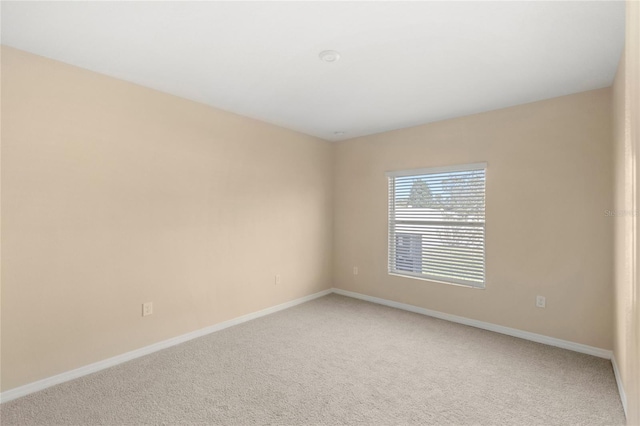 spare room with baseboards and light carpet