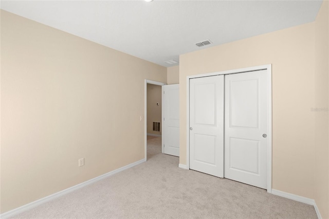 unfurnished bedroom with a closet, visible vents, light colored carpet, and baseboards