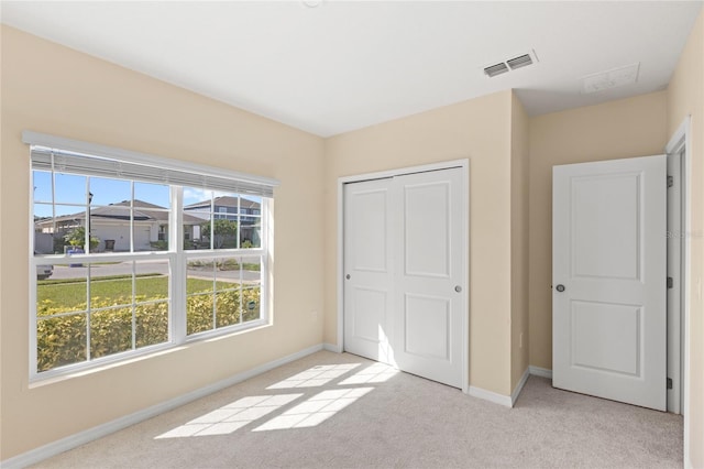 unfurnished bedroom with visible vents, light carpet, baseboards, and a closet