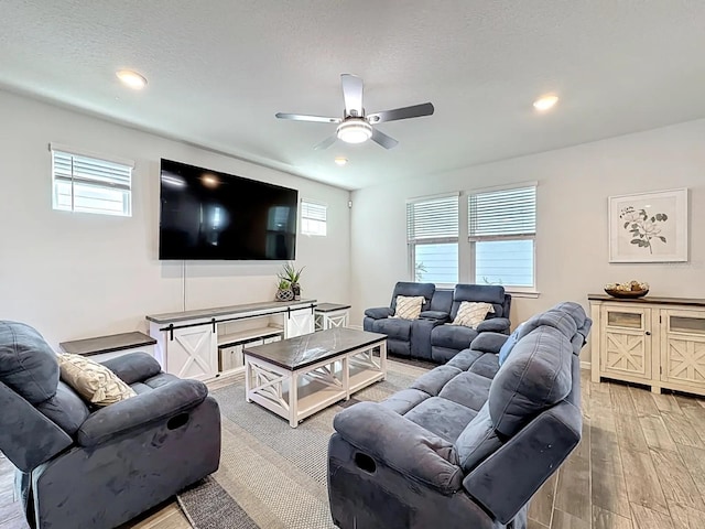 living area with plenty of natural light, a textured ceiling, light wood-type flooring, and a ceiling fan