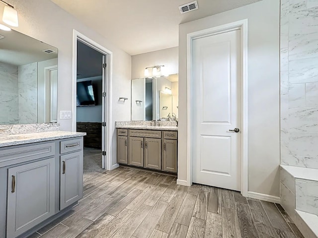 bathroom featuring visible vents, baseboards, two vanities, and wood tiled floor