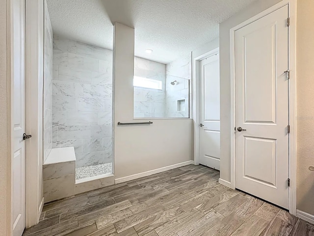 bathroom with baseboards, a textured ceiling, walk in shower, and wood tiled floor