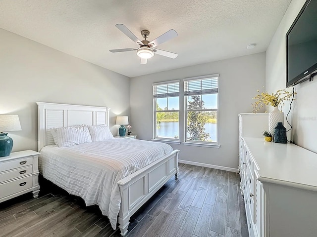 bedroom with baseboards, a ceiling fan, dark wood-style flooring, and a textured ceiling