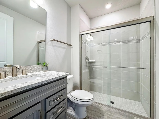 full bath with vanity, a shower stall, and toilet