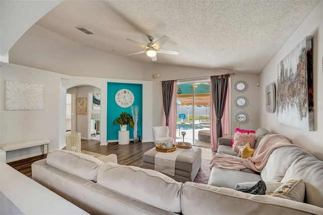 living area with visible vents, a textured ceiling, wood finished floors, arched walkways, and lofted ceiling