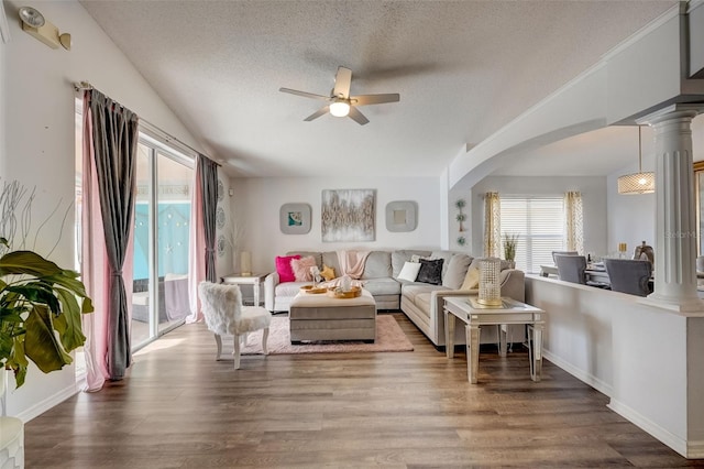 living area with lofted ceiling, a textured ceiling, wood finished floors, and ornate columns