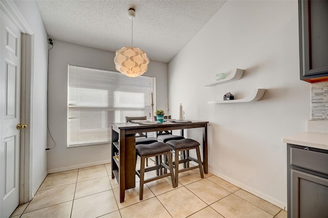 dining room featuring light tile patterned floors, baseboards, and a textured ceiling