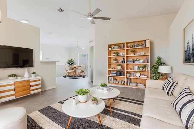 living room featuring a ceiling fan, wood finished floors, visible vents, high vaulted ceiling, and baseboards