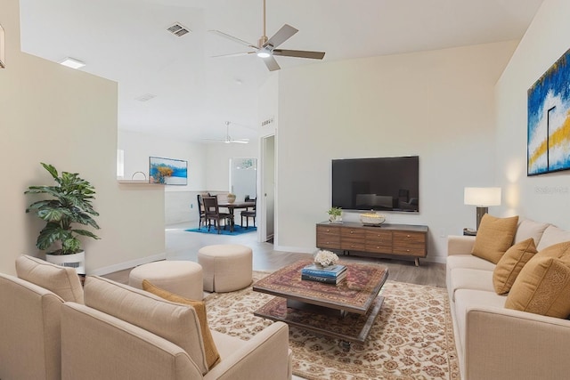 living room featuring visible vents, high vaulted ceiling, a ceiling fan, wood finished floors, and baseboards